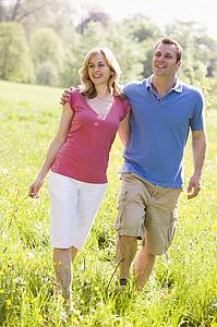 Couple walking outdoors holding flower smiling