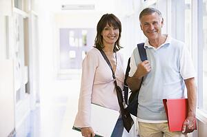 Man and woman standing in corridor with books (high key)