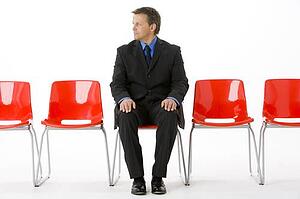 Businessman Sitting In Row Of Empty Chairs 