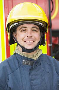 Fireman standing by fire engine wearing helmet