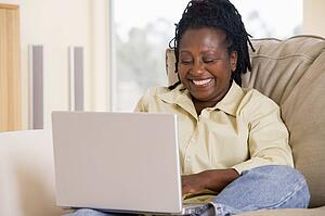 Woman in living room using laptop and smiling