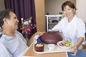 Nurse Serving A Patient A Meal In His Bed
