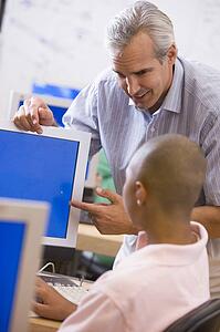Teacher with male student in computer class