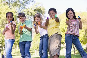 Five young friends with water guns outdoors smiling