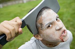 Young boy with scary Halloween make up and plastic knife through head