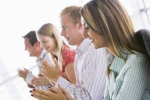 Four businesspeople applauding indoors smiling