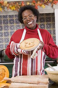 Woman in kitchen making Halloween treats and smiling
