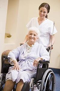 Nurse Pushing Senior Woman In Wheelchair