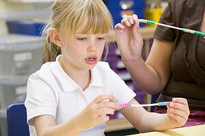 Students in math class using counting beads (selective focus)