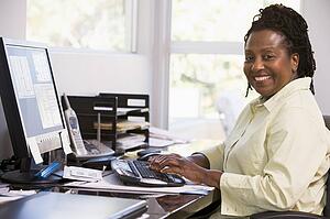 Woman in home office using computer and smiling