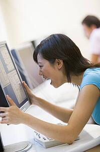 Woman in computer room holding monitor and smiling