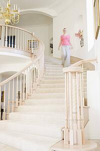 Woman coming down staircase in luxurious home