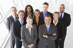 Group of co-workers standing in office space smiling (high key)