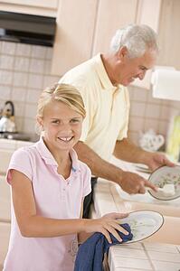 Grandfather And Granddaughter Cleaning Dishes Together
