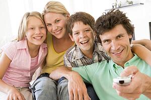 Family in living room with remote control smiling