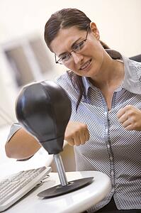 Woman in computer room using small punching bag for stress relief