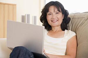 Woman in living room using laptop and smiling