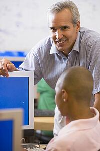 Teacher with male student in computer class