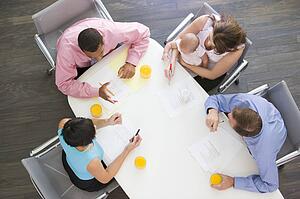 Four businesspeople in boardroom with one holding a baby