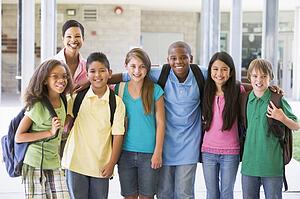 Six students standing outside school with teacher