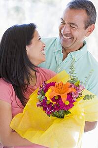 Husband and wife holding flowers and smiling