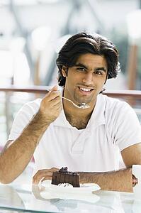 Man at restaurant eating dessert and smiling (selective focus)