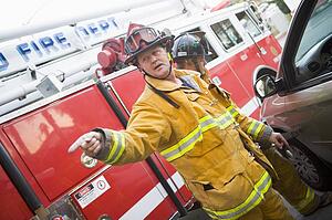 Fireman pointing at something with another fireman using the jaws of life on a car door