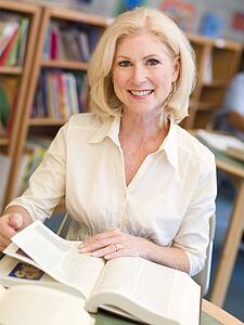 Woman sitting in library with a book (selective focus)