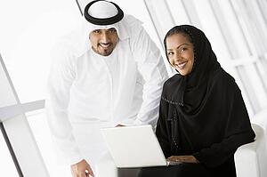 Two people indoors with laptop smiling (high key/selective focus)