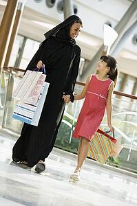 Woman and young girl walking in mall smiling (selective focus)