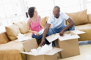 Couple unpacking boxes in new home smiling