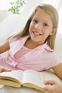Young Girl Sitting On A Sofa Reading A Book