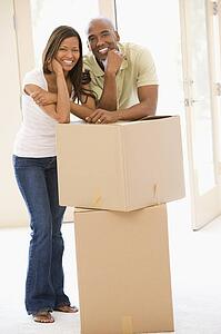Couple with boxes in new home smiling