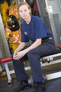 Firewoman sitting on bench in fire station locker room