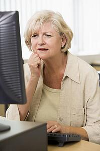Woman sitting at a computer terminal upset (high key)