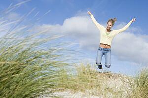 Young woman jumping on a sand hill