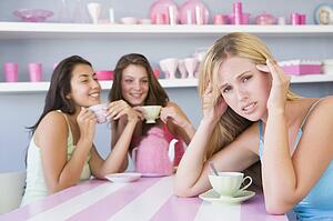 Young woman with a hangover sitting at a table with two friends