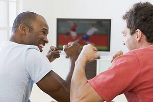 Two men in living room watching television and cheering