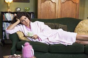 Young woman lying on sofa at home drinking tea