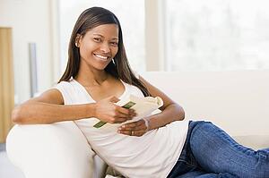 Woman in living room reading book smiling