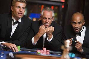 Three men in casino playing roulette (selective focus)