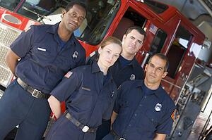 Four firefighters standing in front of fire engine