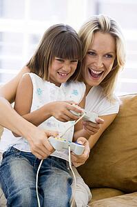 Woman and young girl in living room with video game controllers smiling