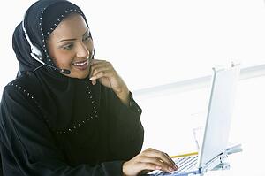 Woman wearing headset with laptop smiling (high key/selective focus)