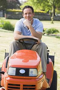 Man outdoors on lawnmower smiling