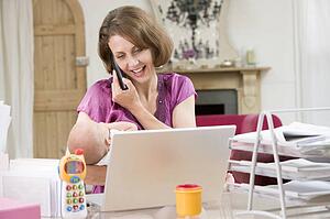 Mother and baby in home office with laptop and telephone