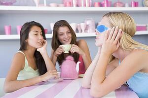 Young woman with a hangover sitting at a table with two friends
