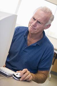 Man at computer looking at monitor confused (high key)