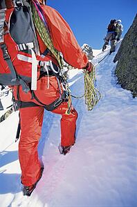 Two mountain climbers going up snowy mountain (selective focus)