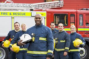 Six firefighters standing by fire engine